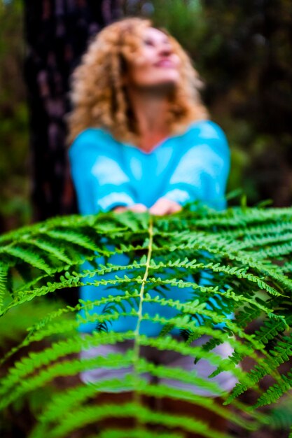 Foto imagem desfocada de uma mulher de pé junto a uma planta na floresta