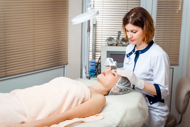 Imagem do belo esteticista fazendo oxigenoterapia para jovem mulher deitada