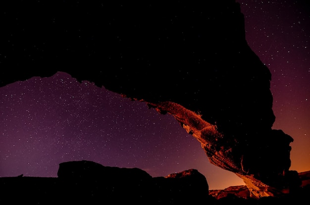 Imagem do céu noturno de um arco natural basáltico