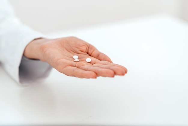 Imagem do close-up da mão de um doutor fêmea com comprimidos.