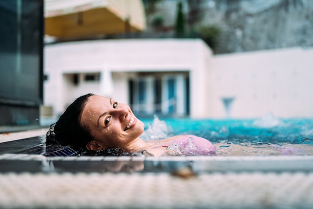 Imagem do close-up da mulher bonita que relaxa em uma banheira de hidromassagem fora.