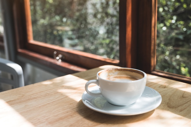 Imagem do close up da xícara de café quente na mesa de madeira vintage no café