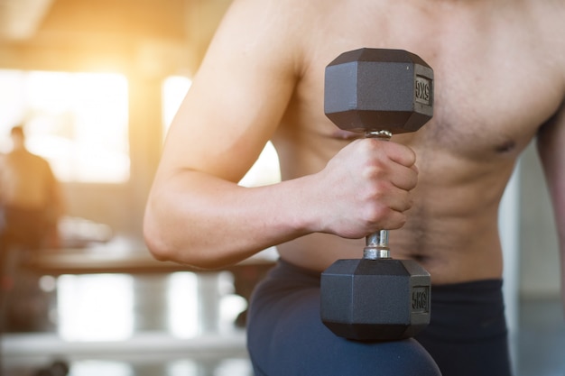 Imagem do close up de pesos de levantamento do homem na frente do fundo sujo da parede no gym velho.