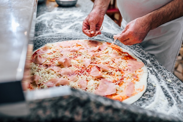 Imagem do close-up do cozinheiro chefe que faz a pizza.