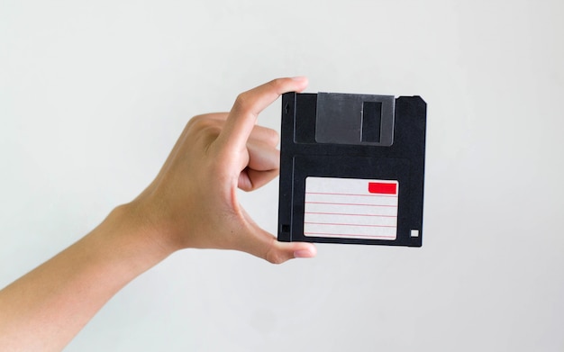 Imagem do close up: mão segurando o armazenamento de dados de disquete preto