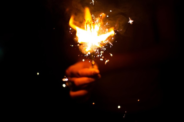 Imagem do conceito de véspera de Natal e ano novo com close-up de um par de mãos de homem pegando um spar de fogo vermelho