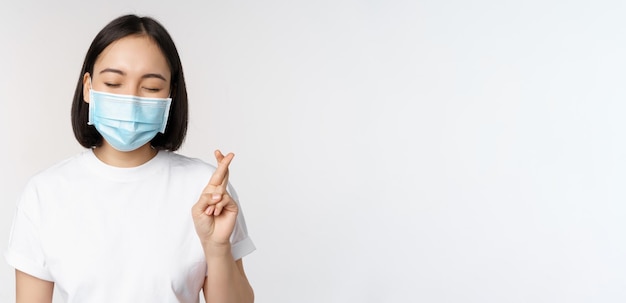 Imagem do conceito médico de saúde e médica da menina asiática em máscara facial médica cruzar os dedos rezando