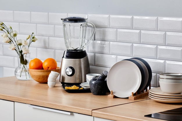 Imagem do conjunto de liquidificador elétrico de placas de cerâmica e outros utensílios de cozinha na mesa na cozinha