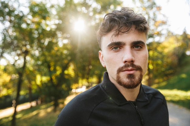 Imagem do corredor de homem de aptidão de esportes jovem bonito ao ar livre no parque.