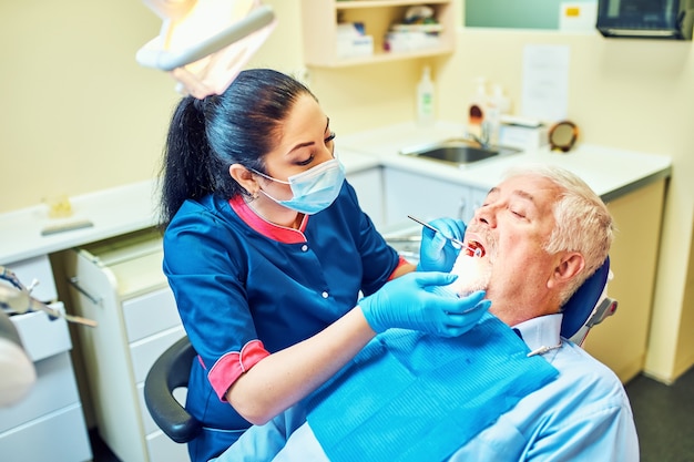 Imagem do dentista usando espelho em ângulo enquanto examina os dentes do paciente