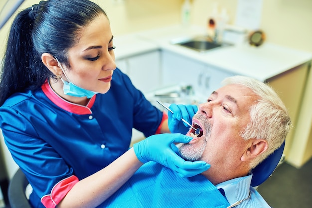 Imagem do dentista usando espelho em ângulo enquanto examina os dentes do paciente