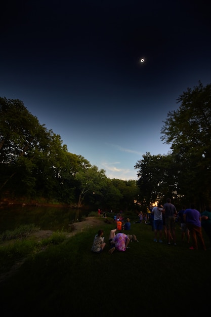 Imagem do eclipse solar visto de um parque com um rio e muitas pessoas em 2017 em Kentucky