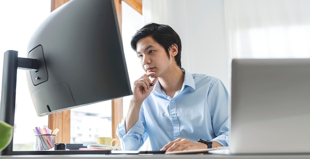 Imagem do empresário asiático confiante trabalhando no escritório e olhando no computador