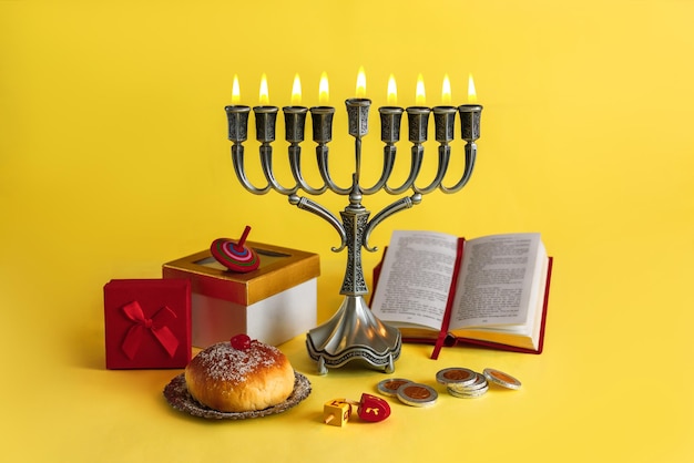 Imagem do feriado judaico Hanukkah com rosquinhas candelabros tradicionais de menorá e piões de madeira girando moedas de chocolate donut em um fundo amarelo