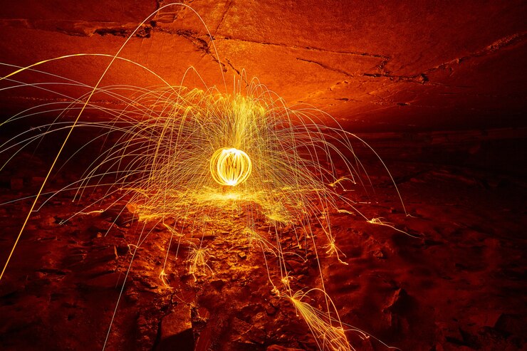Foto imagem do globo de faíscas laranja e amarelas dentro de uma caverna dando um brilho vermelho sinistro