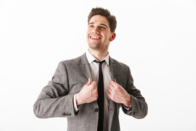 Imagem do homem de negócios feliz segurando o casaco e olhando para longe sobre parede branca