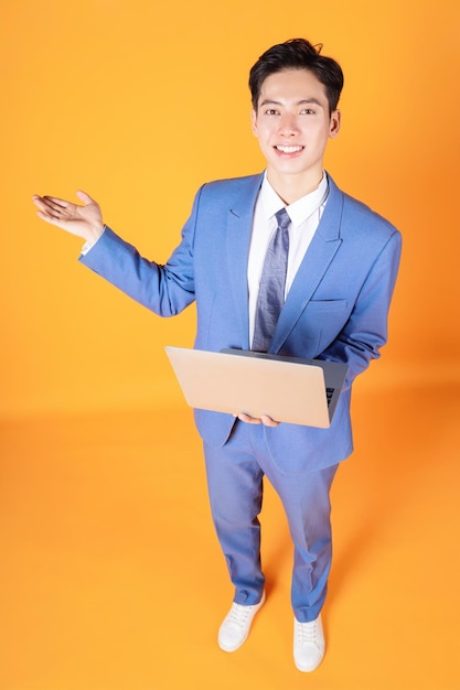 Imagem do jovem empresário asiático usando laptop em segundo plano