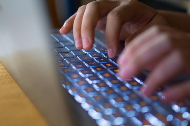 Imagem em close de mãos digitando no teclado do computador portátil e navegando na internet em casa