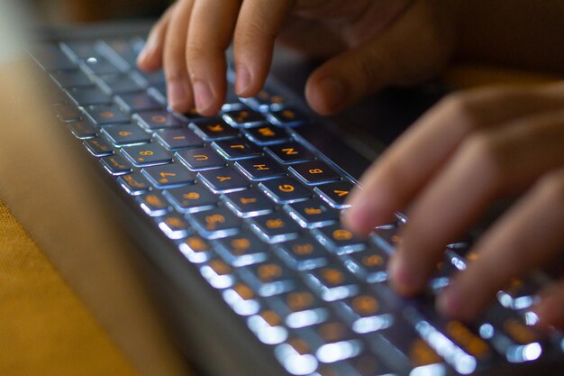 Imagem em close de mãos digitando no teclado do computador portátil e navegando na internet em casa