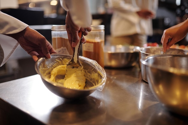 Imagem em close-up de cozinheiro batendo manteiga láctea e sal em uma tigela de metal