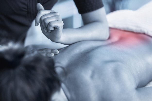 Imagem em close-up de fisioterapeuta massageando paciente feminina com músculo lombar lesionado Imagem colorida azul Acento vermelho nas costas Tratamento de lesões esportivas