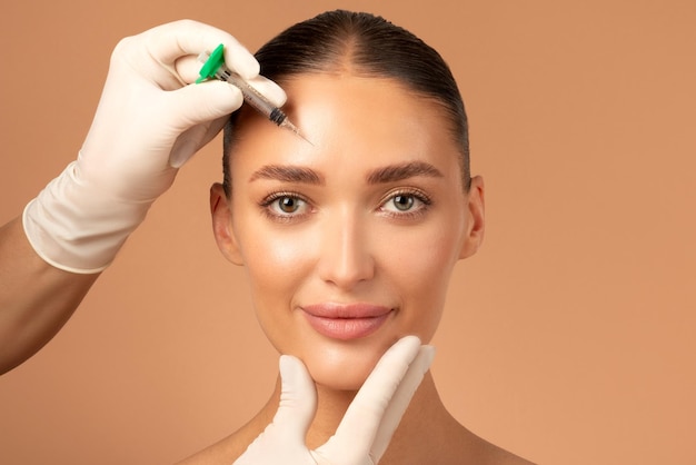 Imagem em close-up de uma mulher recebendo uma injeção na testa de um profissional médico vestido de branco