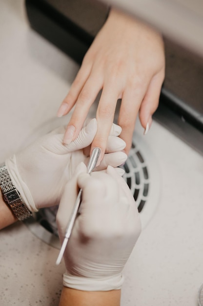 Imagem em close-up do mestre de unhas removendo uma gelatina das unhas do cliente