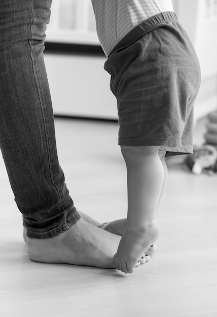 Imagem em preto e branco de close de um menino caminhando para sua mãe na sala de estar