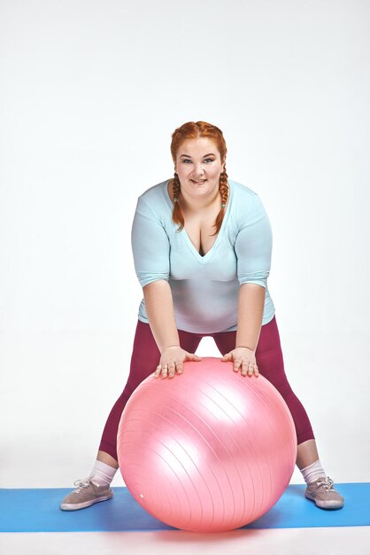 Imagem engraçada de uma mulher ruiva gordinha e divertida segurando uma bola