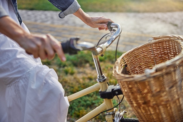 Imagem focada de vista lateral de mãos femininas segurando o guidão de bicicleta ao ar livre