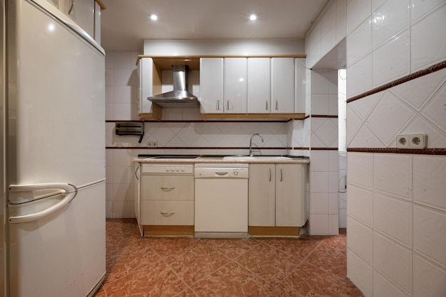 Imagem frontal da cozinha mobiliada com móveis brancos com detalhes em madeira