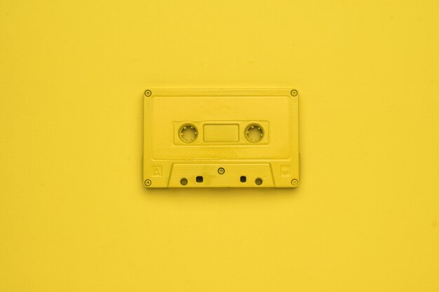 Imagem monocromática de um gravador amarelo sobre um fundo amarelo. Equipamento retro elegante para ouvir música. Postura plana.