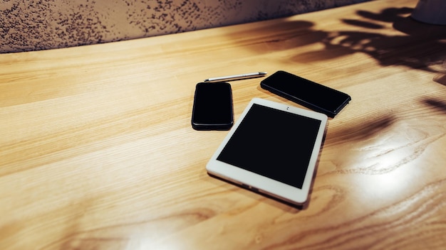 Imagem plana leiga de dois celulares e tablet pc na mesa de madeira