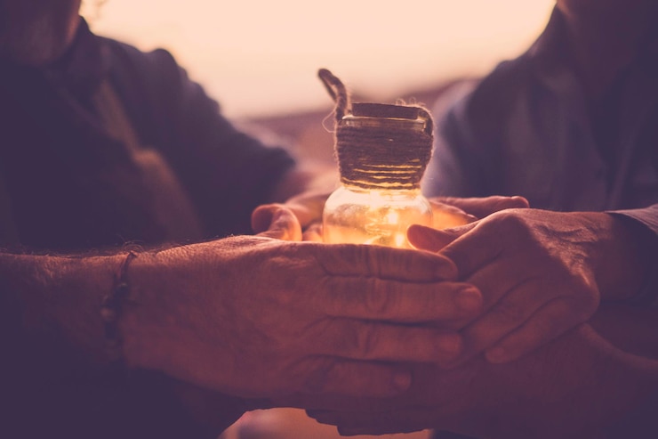 Foto imagem recortada de amigos segurando um frasco iluminado durante o pôr-do-sol