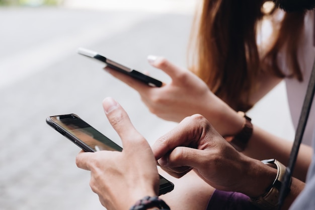 Imagem recortada de amigos usando telefones enquanto estão sentados ao ar livre