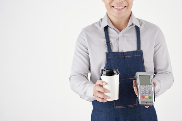 Imagem recortada de barista dando café em copo descartável e terminal de pagamento