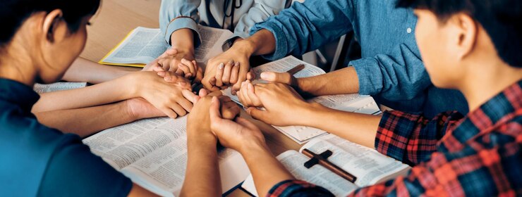 Foto imagem recortada de diversidade pessoas orando juntas em uma igreja de madeira em um livro da bíblia enquanto se dão as mãos juntos com a crença conceito de esperança religião fé deus conceito de bênção burgeoning