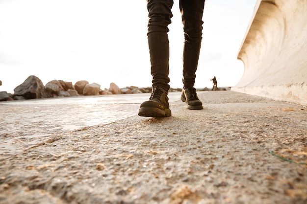 Imagem recortada de homem caminhando na praia.