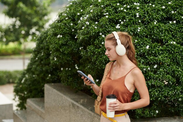 Imagem recortada de jovem empresária ouvindo música e tomando café da manhã