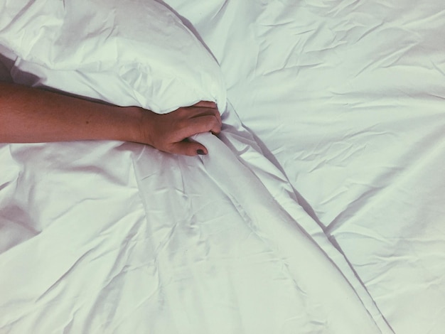 Imagem recortada de mão de mulher em cama branca
