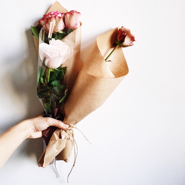 Imagem recortada de mão segurando bouquets contra fundo branco