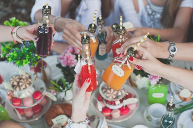 Imagem recortada de mãos aplaudindo bebidas coloridas sobre macarrões em uma festa