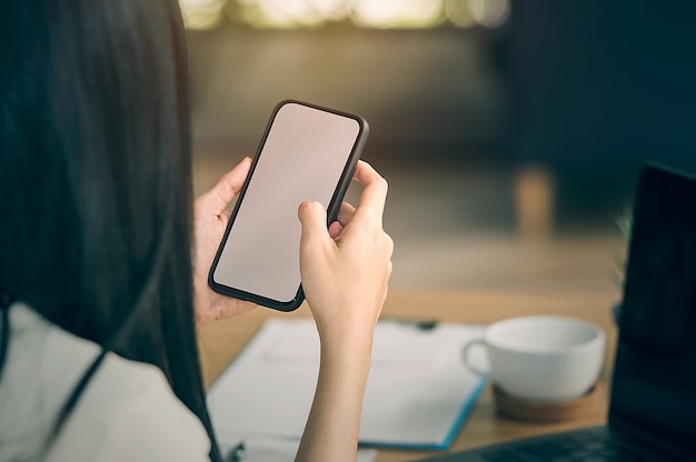 Imagem recortada de mãos femininas segurando o telefone inteligente