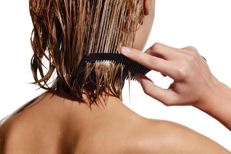 Foto imagem recortada de menina com cabelo molhado escovando o cabelo aplicando máscara de nutrição contra estúdio branco