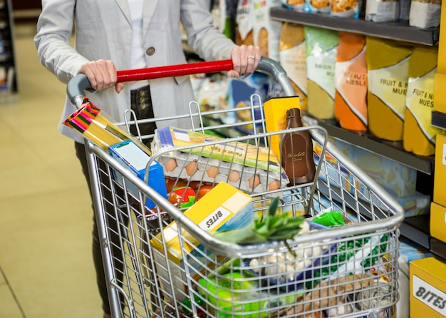 Imagem recortada de mulher empurrando o carrinho no supermercado