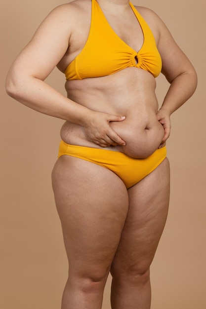 Imagem recortada de mulher gorda com excesso de peso com obesidade adiposo excesso de gordura maiô amarelo Auto-aceitação corporal positiva