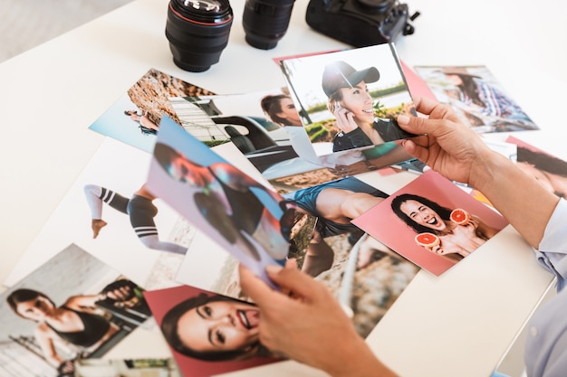 Imagem recortada de mulher jovem fotógrafo no escritório, sente-se à mesa, olhando as fotos.