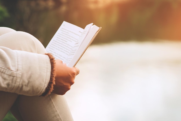 Foto imagem recortada de mulher lendo um livro contra o lago