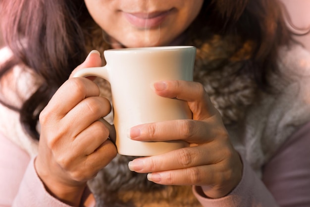Imagem recortada de mulher segurando uma xícara de café
