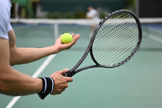 Captura aproximada da mão do tenista masculino segurando a bola de tênis e  o jogo de partida da raquete ou servindo a bola durante a partida